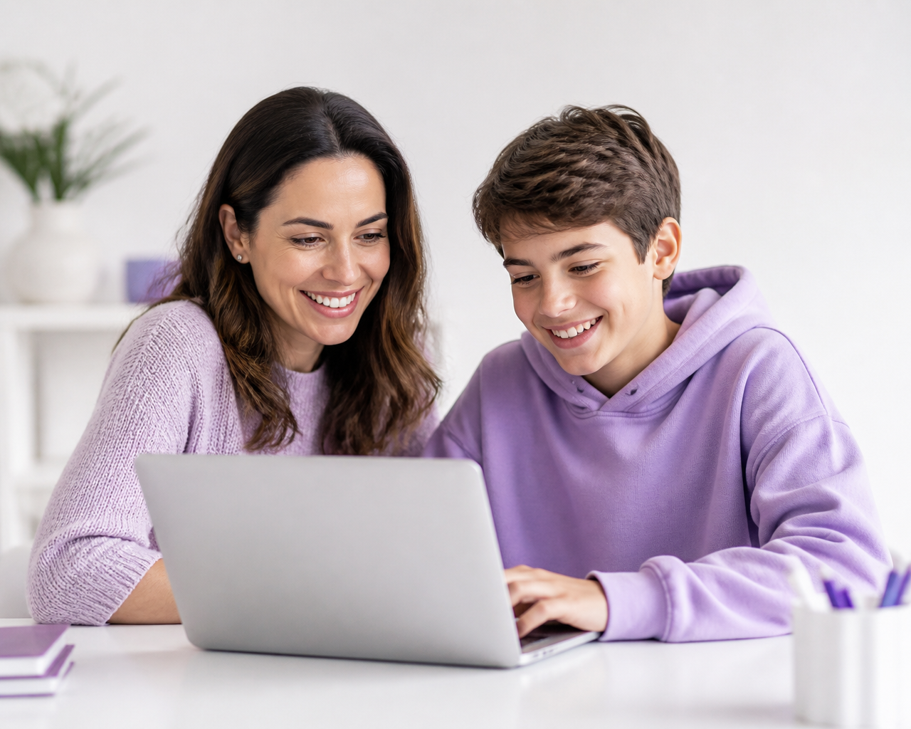 Madre y alumno de GENIA realizando juntos la inscripción en un ordenador portátil